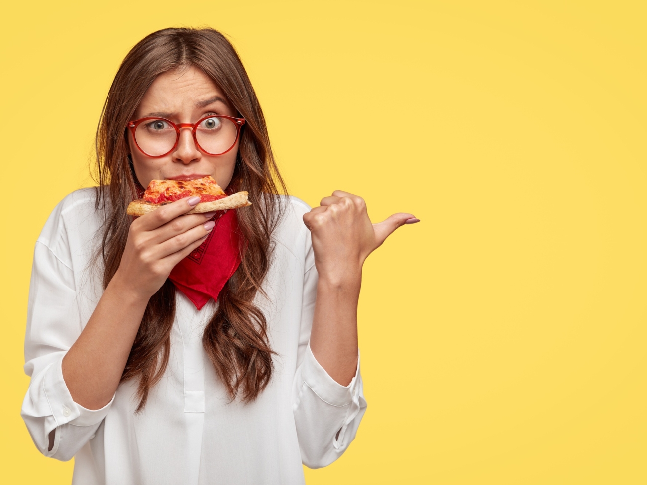 horizontal-shot-of-surprised-female-eats-tasty-slice-of-pizza-dressed-in-fashionable-clothes-indicates-with-thumb-invites-you-to-pizzeria-isolated-over-yellow-wall-people-and-nutrition