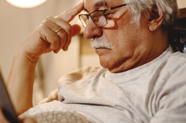 homme-senior-pensif-lisant-livre-tout-se-relaxant-dans-chambre_637285-10427