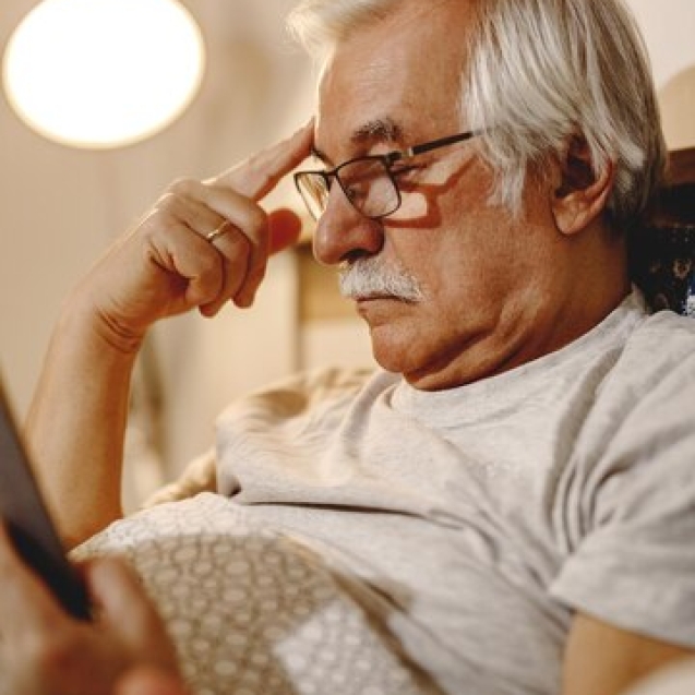 homme-senior-pensif-lisant-livre-tout-se-relaxant-dans-chambre_637285-10427