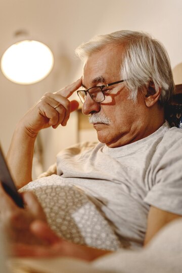 homme-senior-pensif-lisant-livre-tout-se-relaxant-dans-chambre_637285-10427