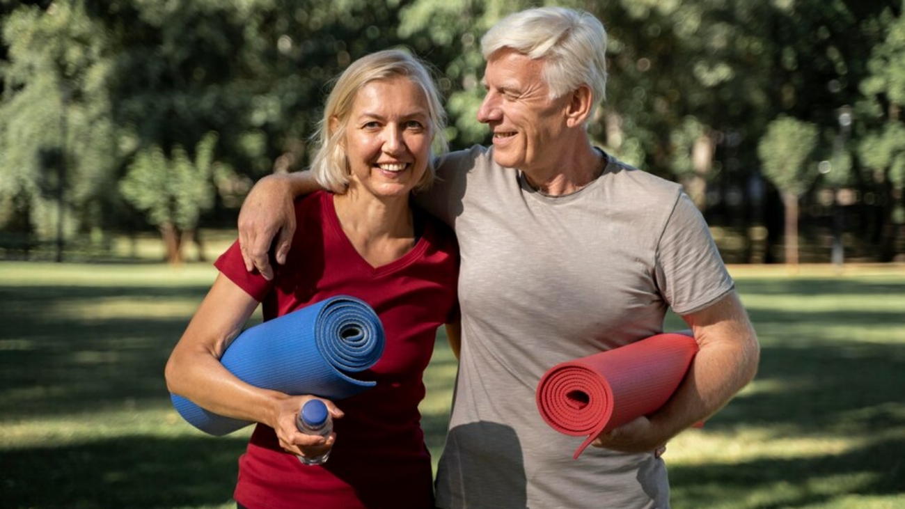 couple-personnes-agees-smiley-exterieur-tapis-yoga-bouteille-eau_23-2148729885