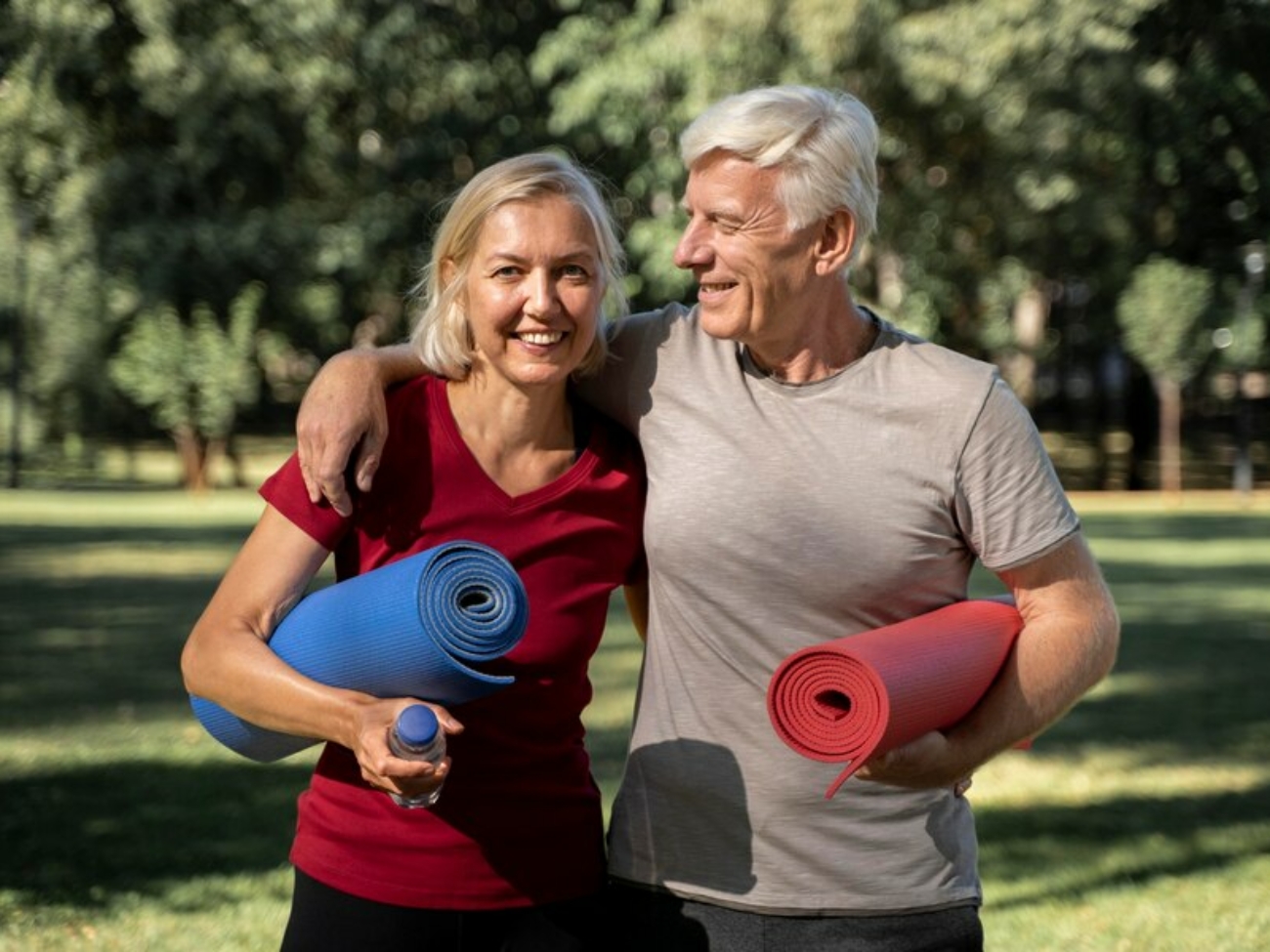 couple-personnes-agees-smiley-exterieur-tapis-yoga-bouteille-eau_23-2148729885